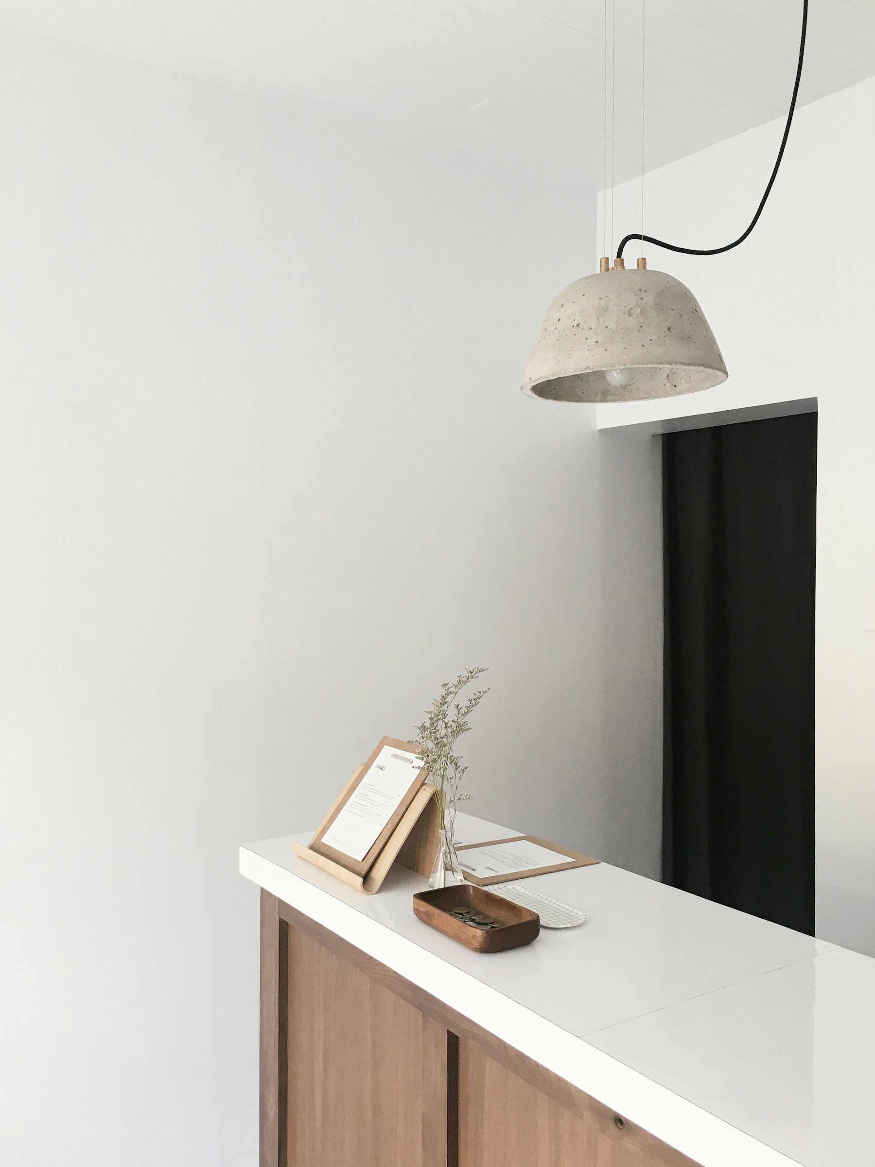 An empty white reception counter under a hanging lamp
