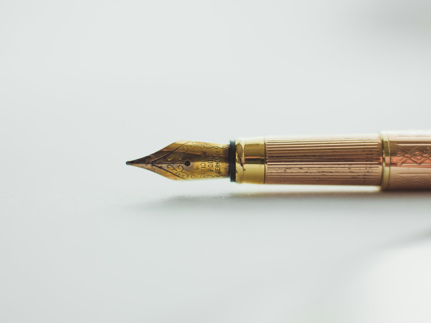 A gold fountain pen nib on a white surface